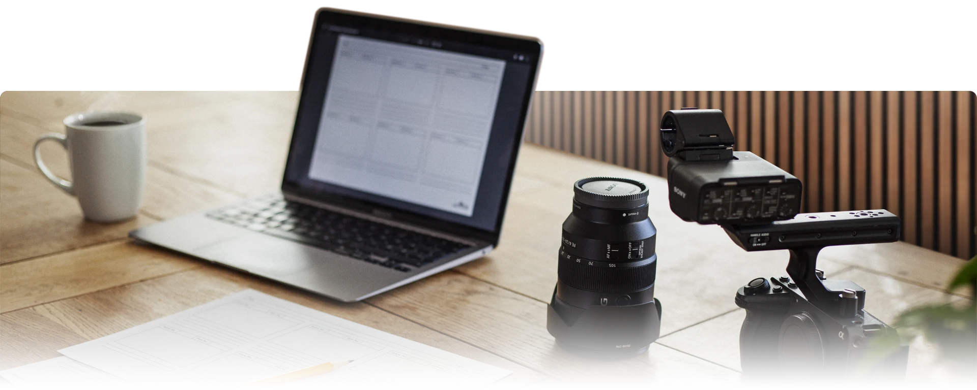 Image of work setup for pre-production, with storyboard, computer, and camera and coffee in a studio environment